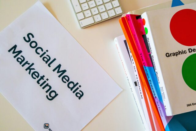 Foglio con scritto "Social Media Marketing" e accanto una pila di libri Foglio con scritto "Social Media Marketing" e accanto una pila di libri