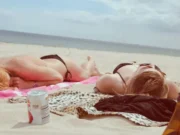 donne in topless distese sulla spiaggia ad abbronzarsi